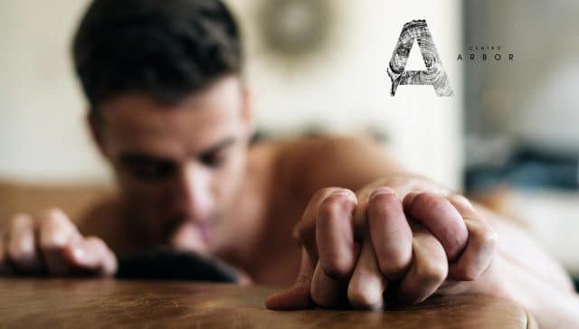 Hombre joven con expresión intensa tumbado, símbolo de adicción sexual y consumo de sustancias