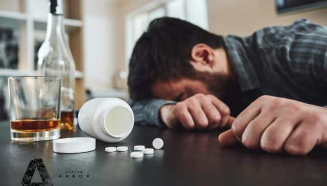 Hombre inconsciente por mezcla de alcohol y pastillas sobre una mesa