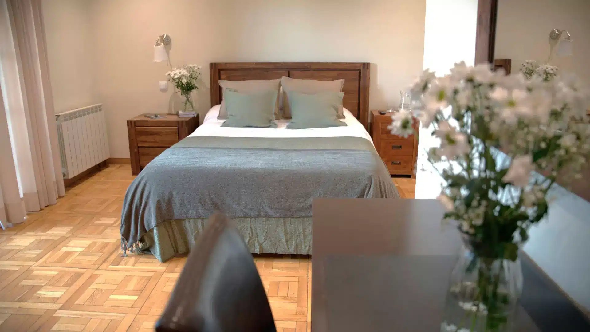 Habitaciones en el Centro de Desintoxicación Árbor: bienestar y descanso en cada detalle Habitación luminosa y cuidada con cama doble, flores y mobiliario de madera en el Centro Árbor de Soto del Real, Madrid.