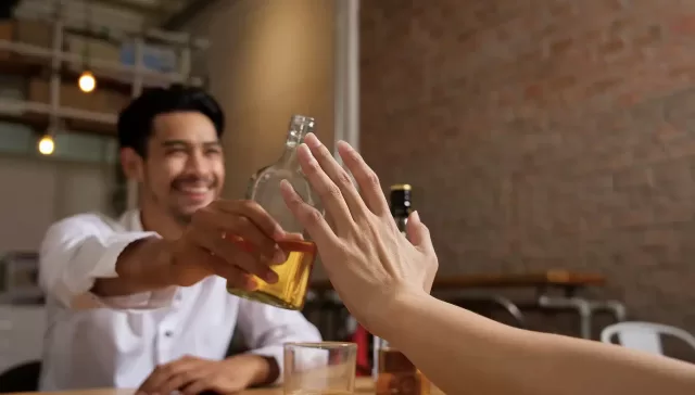 Persona sentada sola en casa con una copa en la mano, representando el alcoholismo silencioso.